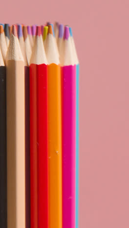 Vertical-Video-Studio-Shot-Of-Rotating-Multi-Coloured-Pencils-Against-Pink-Background-1